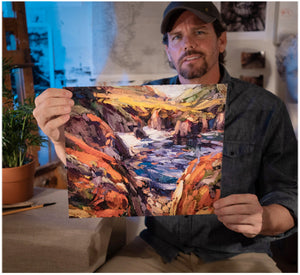Painter Sean Diediker holding a print of his art Red Cliffs on Highway 1 in Big Sur California as part of Canvasing The World TV show on PBS.